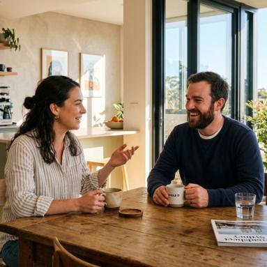 Couple having a relaxed conversation over coffee in a modern Australian apartment
